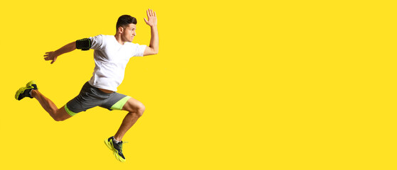 Sporty male runner on yellow background with space for text - obrazy, fototapety, plakaty