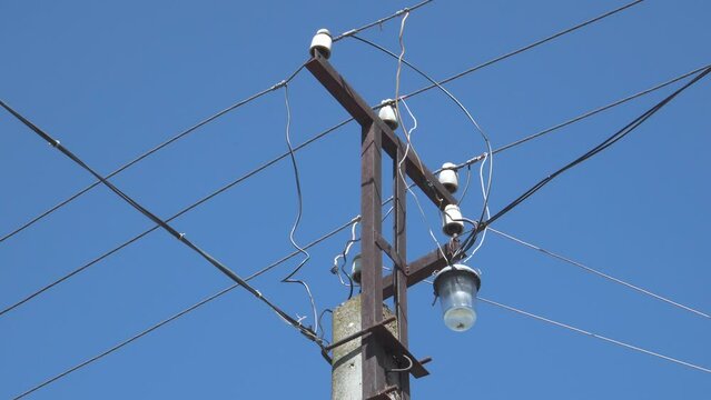 An electric pole with wires connected to it against a blue sky.