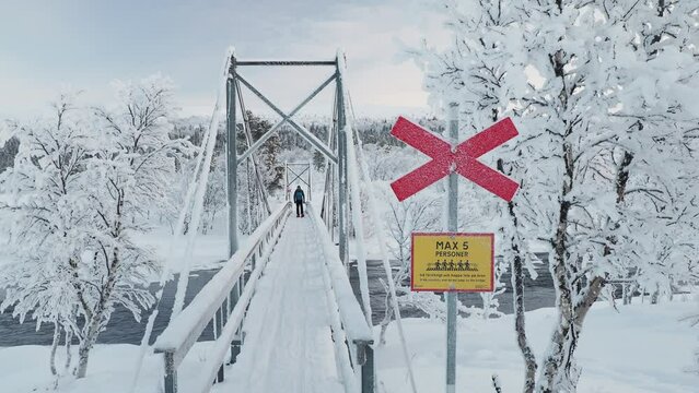 Man walking on bridge with snowshoes