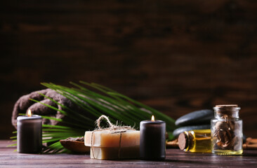 Soap bars and burning candles on wooden table