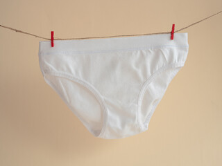 White panties for girls hanging on a rope attached with a clothespin, children's knitted cotton...