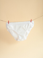 White panties for girls hanging on a rope attached with a clothespin, children's knitted cotton...
