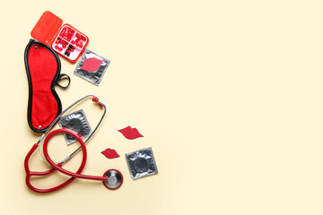 Stethoscope with condoms, pills, blindfold and paper lips on beige background