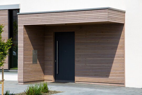 Schöner Eingangsbereich an einem neuen Wohnhaus mit moderner Haustür und Holzpaneelen