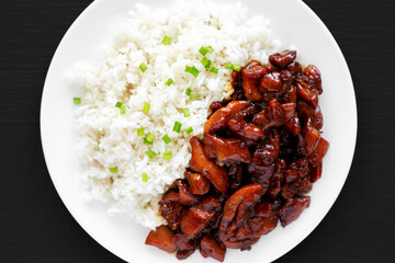 Homemade Teriyaki Chicken with White Rice on a Plate on a black background, top view. Flat lay, overhead, from above.
