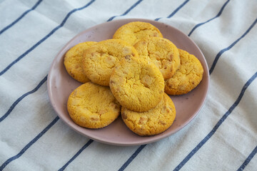 Homemade Lemon and White Chocolate Cookies on a Plate on a white wooden background, side view.