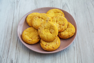 Homemade Lemon and White Chocolate Cookies on a Plate on a white wooden background, side view.