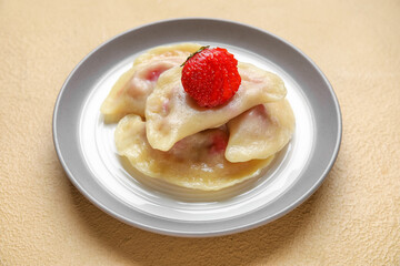 Plate with strawberry dumplings on color background, closeup