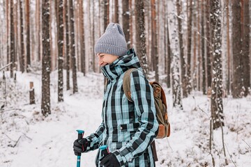 Fototapeta premium Nordic walking. Active sports. Young athletic woman practicing walking outdoors. Winter snowy forest