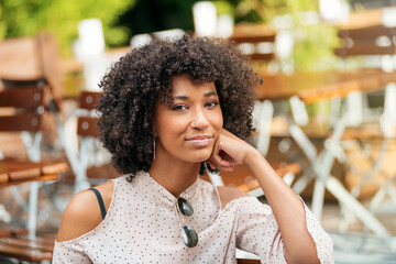 Charming black woman sitting on terrace