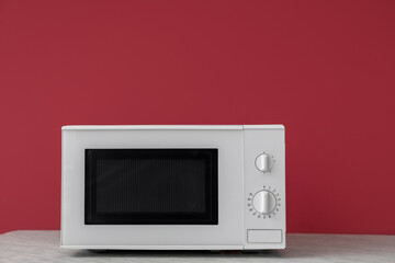 Obraz premium Modern microwave oven on wooden table against color background