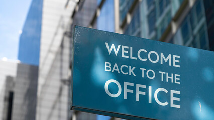 Welcome back to the Office on a blue city-center sign in front of a modern office building	