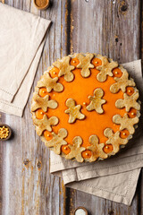 Traditional American pumpkin pie with gingerbread man on wooden background for Thanksgiving. Copy space top view.