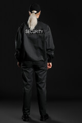 Female security guard on dark background, back view