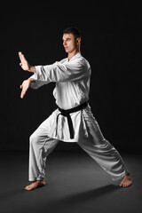 Man practicing karate on dark background