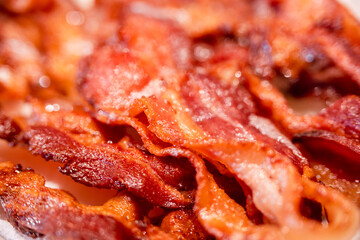 Macro view of appetizing, tasty, fried, crispy bacon slices, close-up, meat ham to scrambled eggs, shallow depth of field