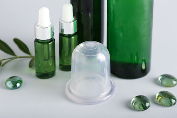 Vacuum jar for anti-cellulite massage and bottles of essential oil on white background