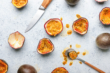 Delicious cut passion fruits, spoon and knife on light background