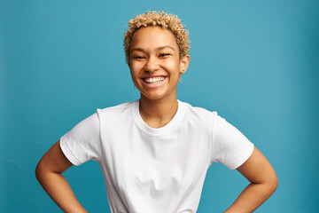 Horizontal image of cheerful overjoyed female with lovely blonde curls in white mockup t-shirt...