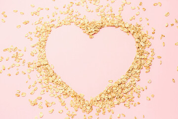 Heart made of raw oatmeal on pink background