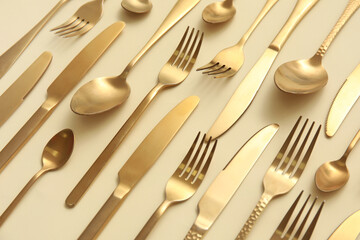 Many different golden cutlery on color background