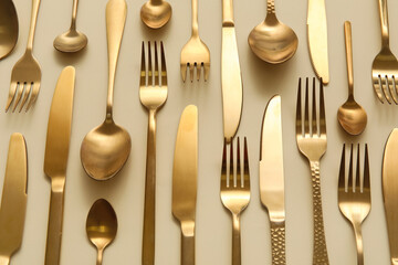 Many different golden cutlery on color background