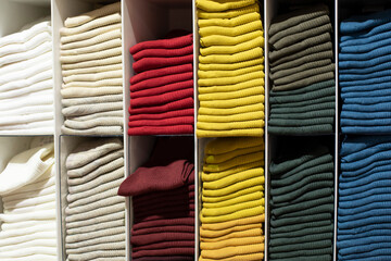 Knitwear on the shelf in the store, knitted clothes of different colors laid out in cabinets