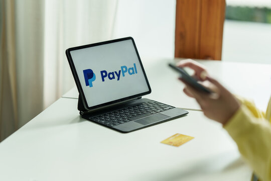 CHIANG MAI, THAILAND - MAY 11 2022 : Woman using Ipad with paypal logo on screen. PayPal is a worldwide online payment system and one of the most popular ways of making payment on the Internet.