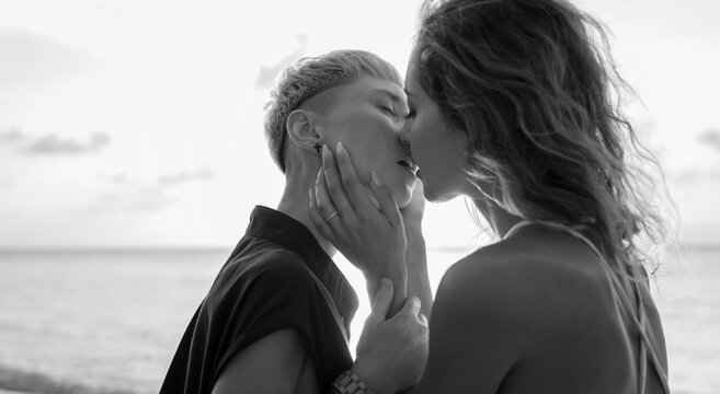 Kiss of two beautiful young sensual lesbian women on the seashore, black and white image. lgbt family