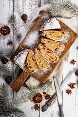 Christmas stollen on a cutting board. Wooden white table background. Traditional Christmas pastry with marzipan, nuts, raisins and dried fruit. Top view