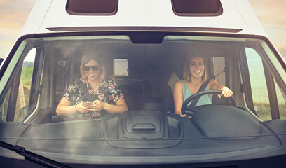 Front view through windshield of happy female friends traveling in camper van