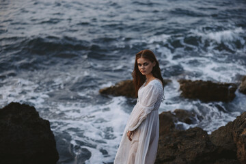 Fototapeta na wymiar pretty woman with wet hair in white dress cliff
