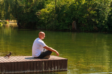 Bald man relax, siting on beach Wooden pier walk on sunny day in park on lake thinking and concentrate in the summer background with copy space for label text banner or advertisement.