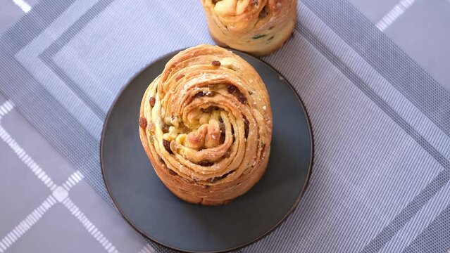 young woman puts fresh baked easter cake cruffin on kitchen table