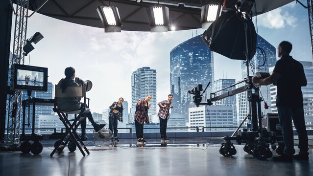 Music Clip Studio Set: Shooting Hip Hop Video Dance Scene with Three Professionals Dancers Performing on Stage with Big Led Screen with Modern City Background. Director and Cameraman in Backstage.