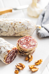 Traditional sausage with white mold. Dried sliced pork salami on cutting board.