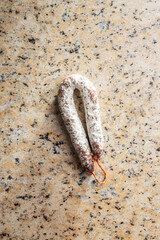 Traditional sausage with white mold. Dried pork salami on kitchen table.