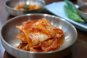 Cabbage kimchi is served on a stainless steel plate.