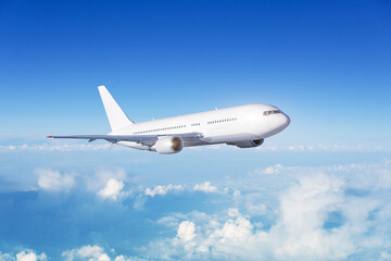 White passenger wide body plane. Aircraft is flying in blue cloudy sky.