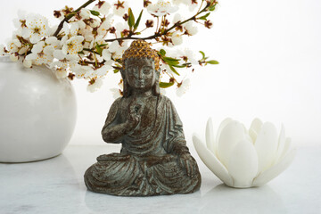 Vesak, Wesak, Buddha birthday. Buddha statue with blossoming cherry on white background. Spa ritual. Mental health and meditation.