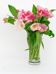 bouquet of pink tulips in a glass glass on a white background with a copy of the space