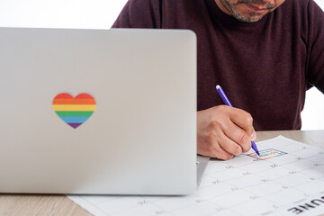 Unrecognizable mature man marking on a calendar the date of the International LGBTQ Pride Day, next...