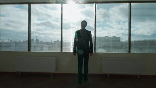 Blurred view, business motivation, businessman stands in front of a panoramic window, morning in a modern office, natural lighting, the thinking process., 4k slow motion.