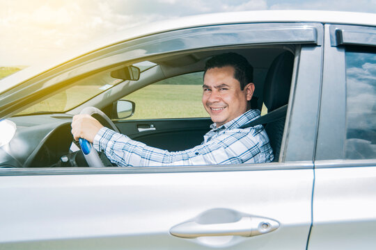 man smiling at the camera in his car, man smiling happily in his car, image of a person smiling and happy driving a car and looking at the camera