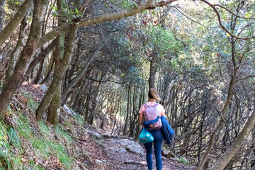 Active woman with backpack walking on hiking trail Path of Gods between Positano and Praiano, Amalfi Coast, Campania, Italy, Europe. Trekking through dense forest at Mediterranean Sea
