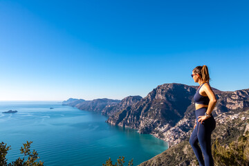 Woman with panoramic view from hiking trail Path of Gods between coastal towns Positano and Praiano. Trekking in Lattari Mountains, Apennines, Amalfi Coast, Campania, Italy, Europe. Mediterranean Sea