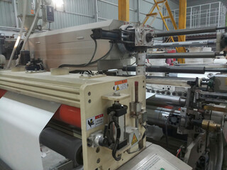 Kolkata, West Bengal, India - 12th January 2019 : Extruder and roller running for coating polyethylene , PE on paper, for making paper cups.