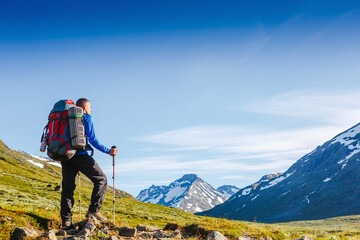Hiker hiking with backpack looking at mountain view. Norway landscape