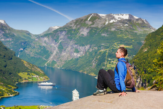 Picturesque Norway mountain landscape. Young man enjoying the view near Geiranger fjord, Norway