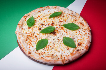 Italian pizza four cheeses with basil leaves on a white-red-green background 